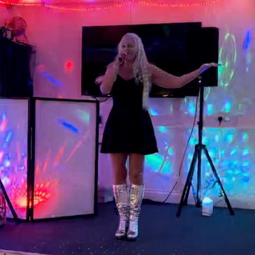 Woman singing on stage with colorful lights.