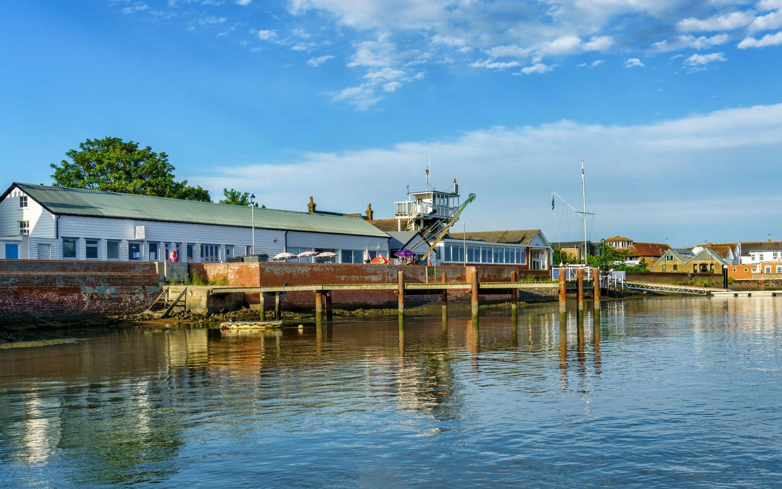 Calm waterfront with buildings and docks under a bright blue sky.