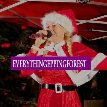 Woman in Santa outfit singing into microphone.