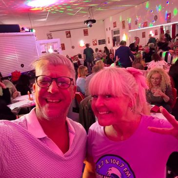 Two people smiling at a lively party or club.