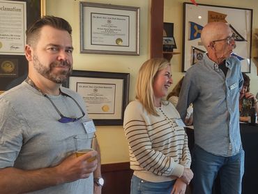 Three adults standing and smiling indoors.