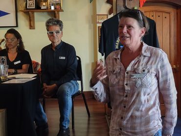 A woman speaking to an audience with two people listening.