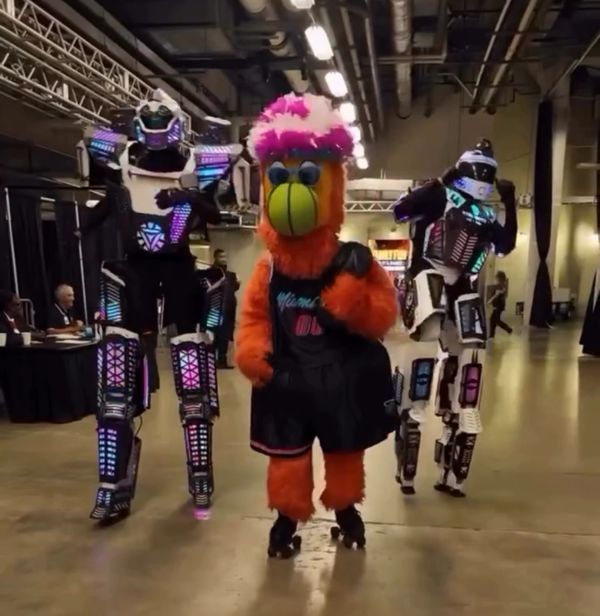 Three performers in colorful LED and furry costumes indoors.