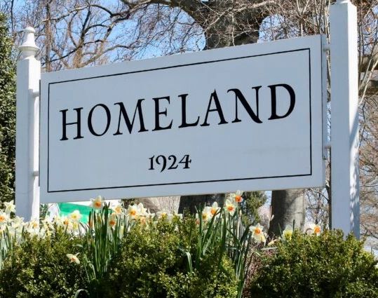 Sign reading "HOMELAND 1924" surrounded by flowers and greenery.
