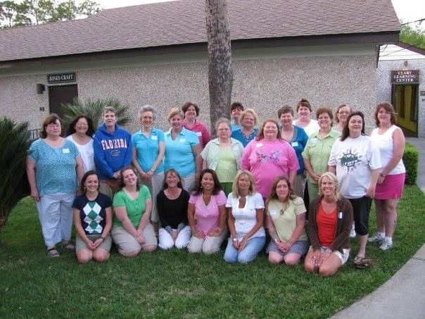 Group of women posing outdoors in front of building.