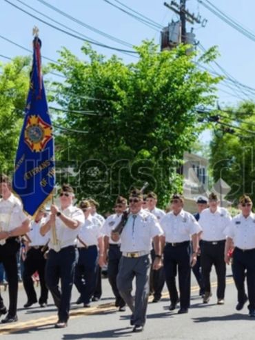 Veterans marching in a parade holding flags.