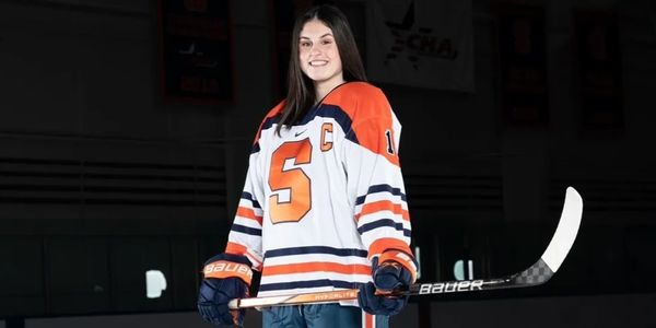 Female hockey player in Syracuse jersey holding a hockey stick.