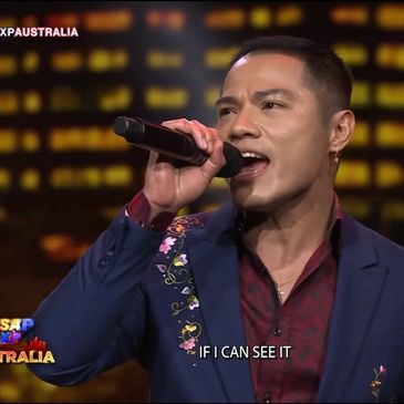 Man singing passionately on stage with a microphone.
