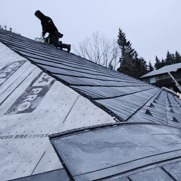 Person working on a sloped roof installing new tiles.