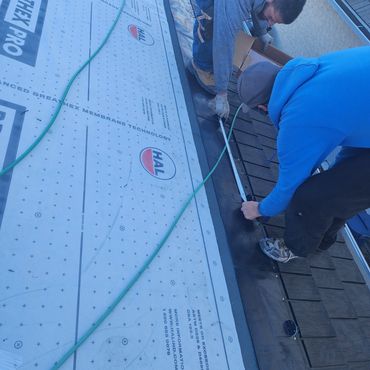 Two workers measuring and installing roofing material.