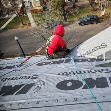 Person working on a roof with safety harness.