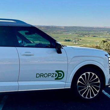 White SUV with DROPZ logo parked in a scenic outdoor location.