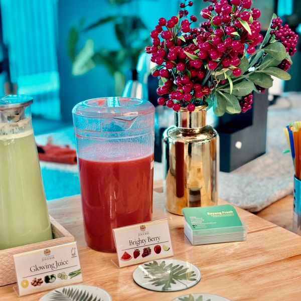 Two juices and a berry bouquet on a wooden counter.