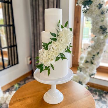 3 tier white wedding cake with rose, lisianthus and foliage cascade.