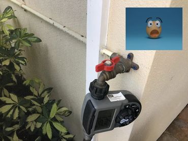 Outdoor water faucet with a digital timer attached to the wall.