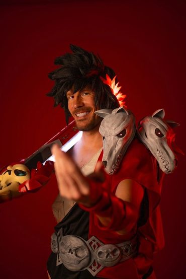 Zagreus cosplay in the traditional pose from the game, reaching out to the audience