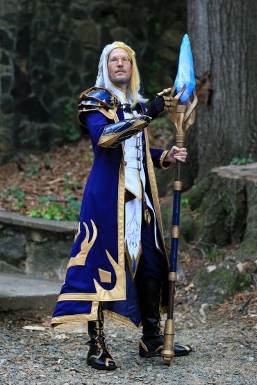 A person in an elaborate fantasy costume holding a blue staff.