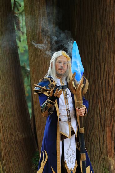 Cosplayer dressed as a wizard with glowing blue staff.