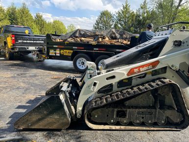 Bobcat skid steer loader with trailer and truck loaded with firewood.
