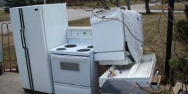 Old appliances including a refrigerator and stove left outdoors.