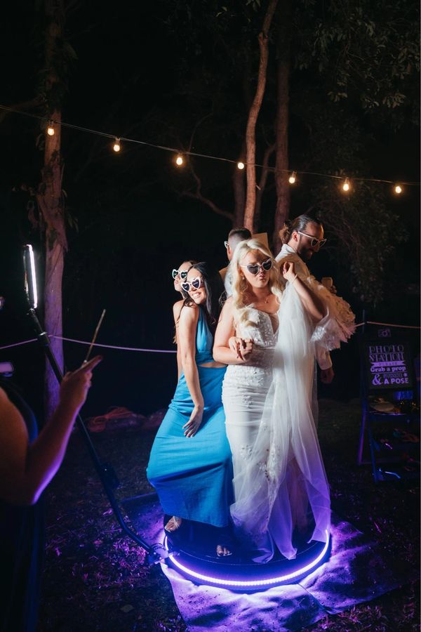 Bride with photo props on the 360 photo booth. 360 video booth at wedding