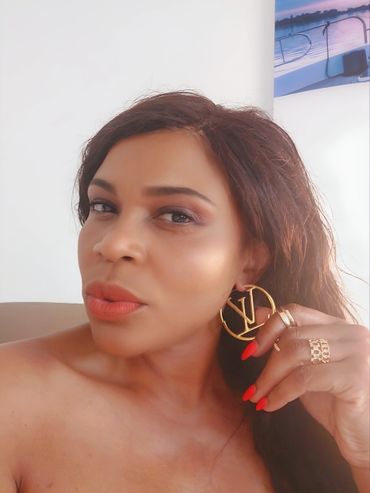 Woman showing off large gold LV earrings and red nails.