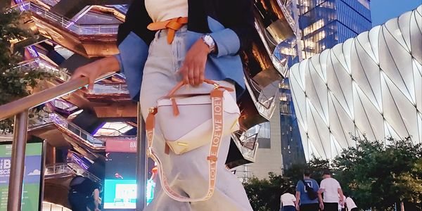 Woman posing confidently in stylish outfit near modern architectural structure at dusk.