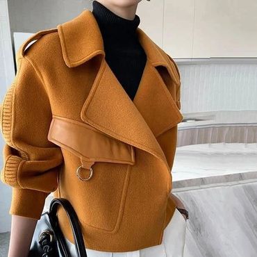 Fashionable outfit with a mustard jacket and white pants, accessorized with a black handbag.