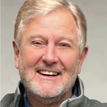 Smiling elderly man with gray hair and beard.