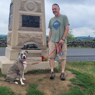 Man with his dog at a monument outdoors.