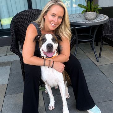 Woman happily embracing her dog while sitting outdoors.
