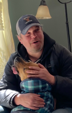 Man smiling while petting a dog.