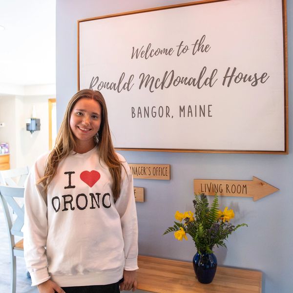 Smiling woman in an 'I love Orono' sweatshirt at Ronald McDonald House, Bangor.