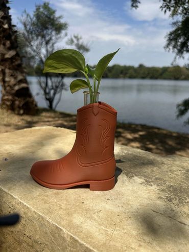 Cowboy Boot Propagation Planter with a plastic test tube and green plant cutting by a lake