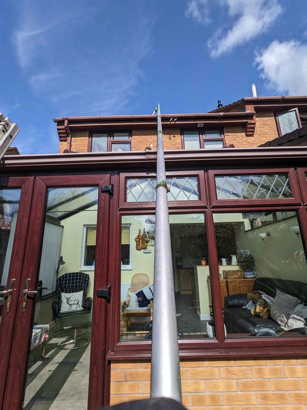 A long telescopic pole reaching a house roof.