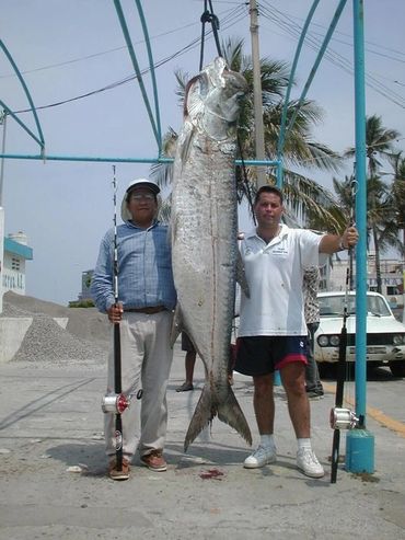 Two men standing beside a large fish