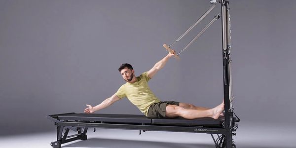 Man exercising on a reformer Pilates machine with resistance bands.