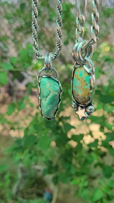 Two turquoise stone pendants with silver chains against a blurred green background.