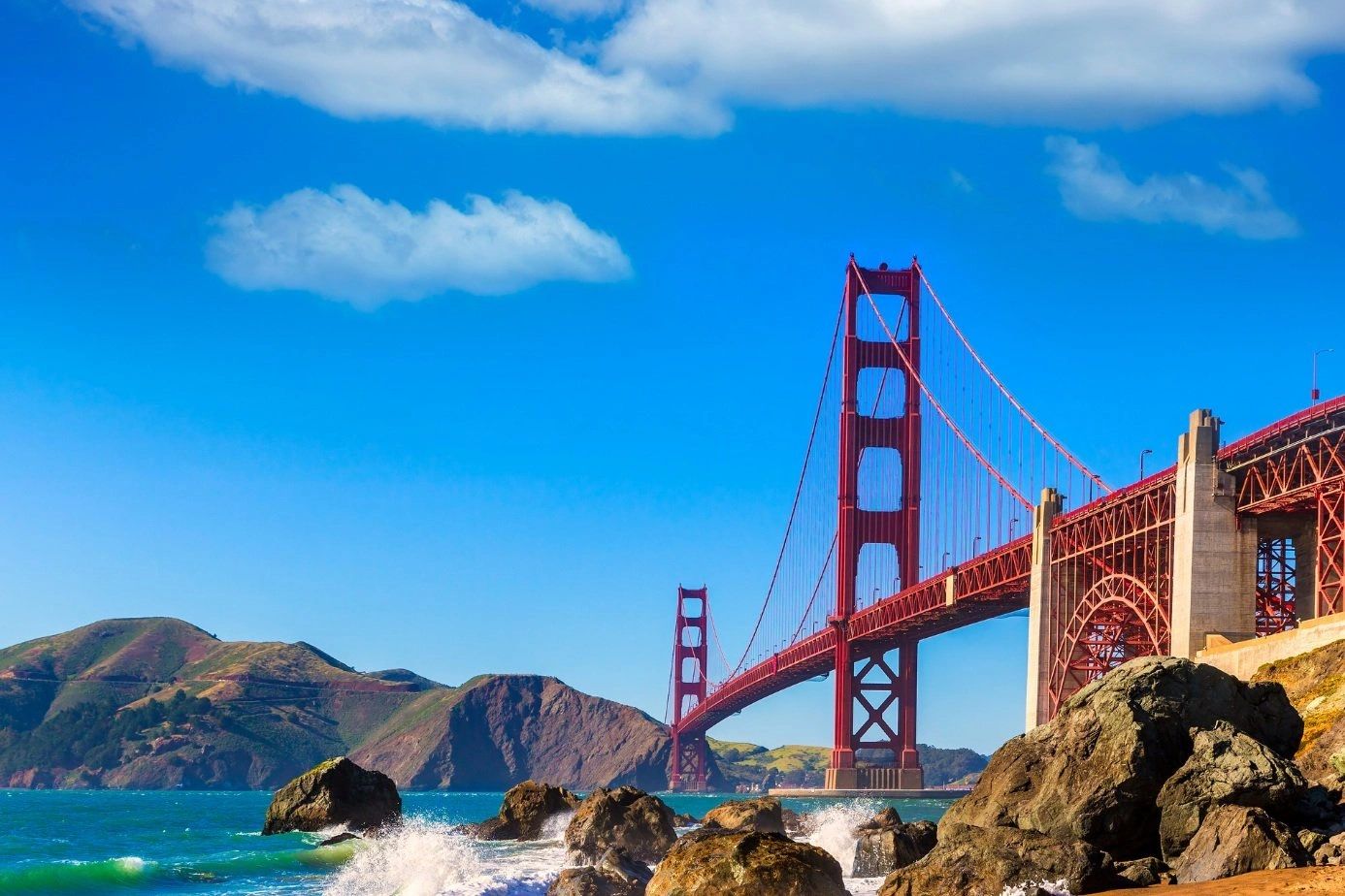 Golden Gate Bridge with clear blue sky and rocky shore.