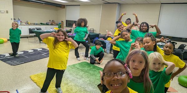 Group of kids posing playfully in colorful shirts indoors.