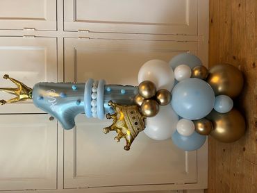 A festive balloon arrangement with a large number one and crowns.