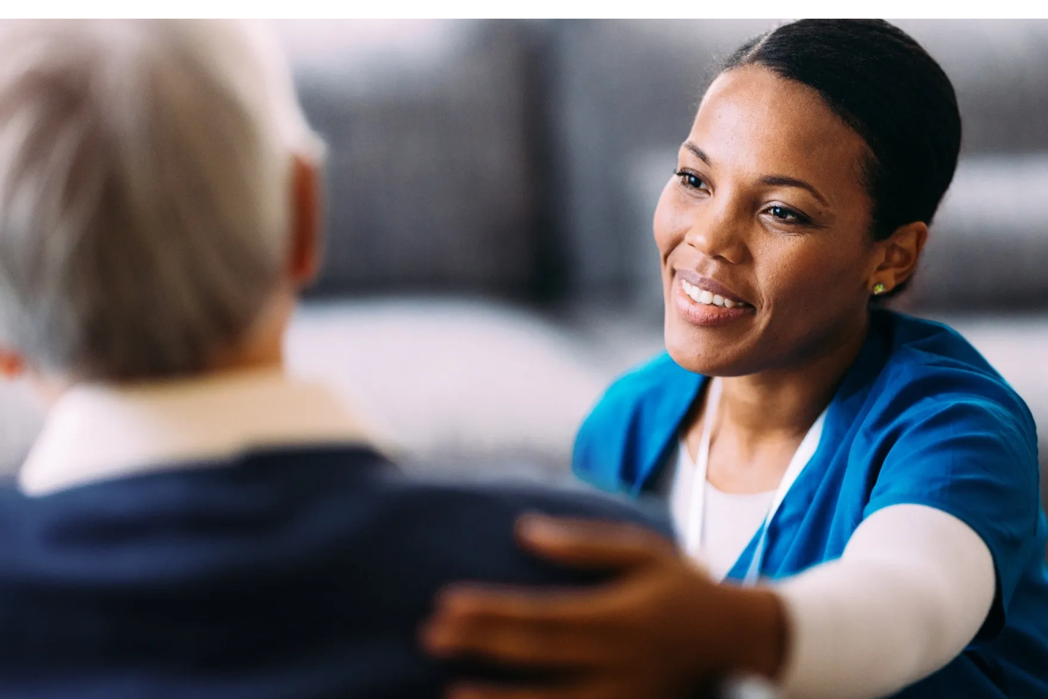 A compassionate nurse comforting an elderly patient with a warm smile.