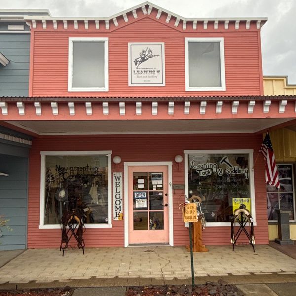 Front view of a pink tack and saddlery shop with displays and signs.