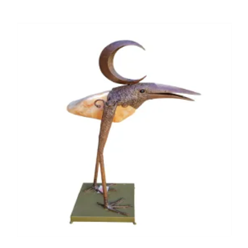 Escultura metálica de un pájaro con media luna.