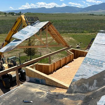 telehandler maneuvering wood trusses onto house remodel
