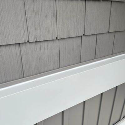 close up photo of siding, shake on top followed by an aluminum frieze board, then vertical vinyl.