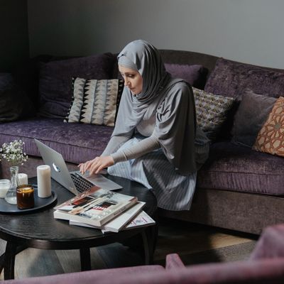 Woman wearing a hijab, sitting on a computer, studying English online