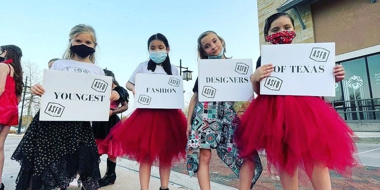 Group of girls with signs stating the Youngest Fashion Designers of Texas for fashion show