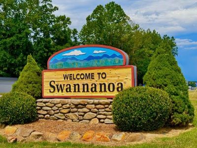 Welcome sign for Swannanoa surrounded by greenery and a stone base.
