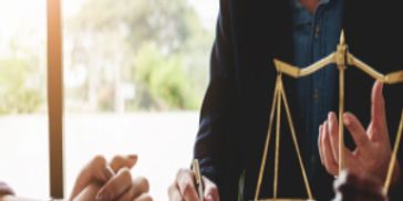 Lawyer consulting a client with legal symbols on the desk.